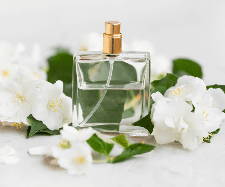 A perfume bottle surrounded by blooming white flowers