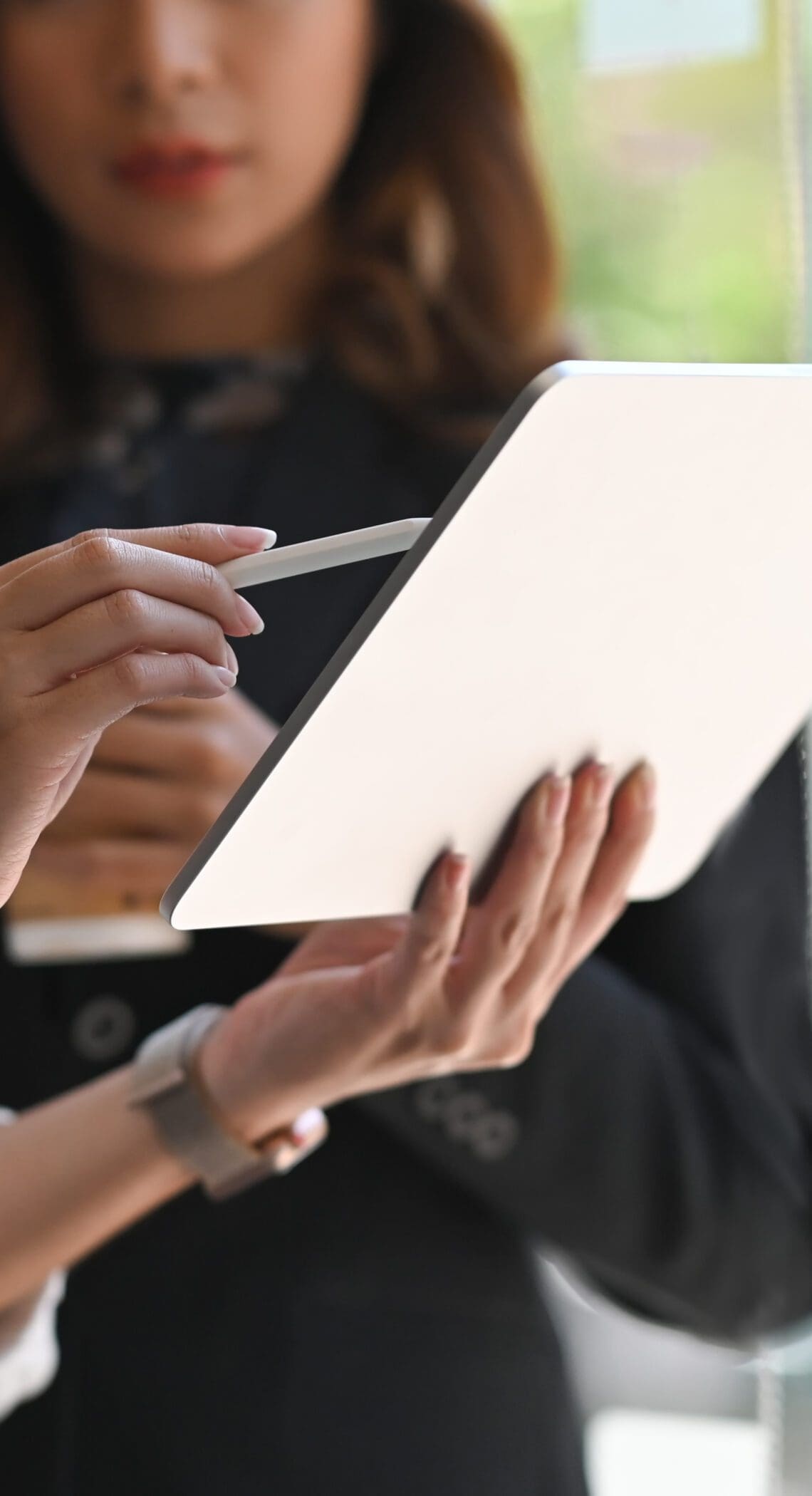 Two individuals collaborating while holding a tablet
