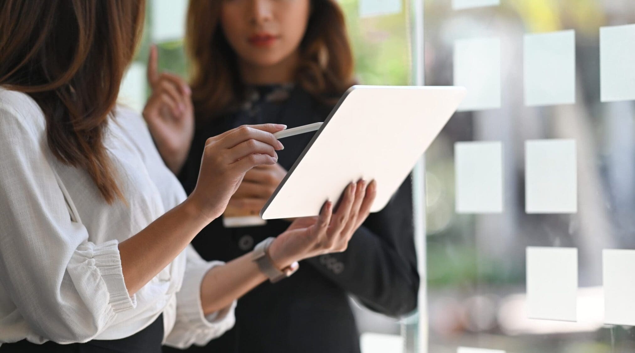 Two individuals collaborating while holding a tablet