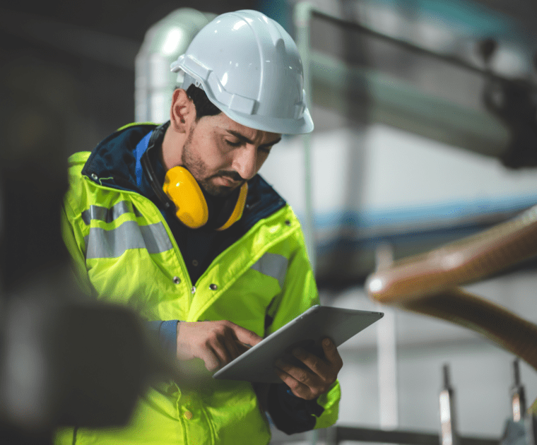 Employee in a reflective vest reading a tablet