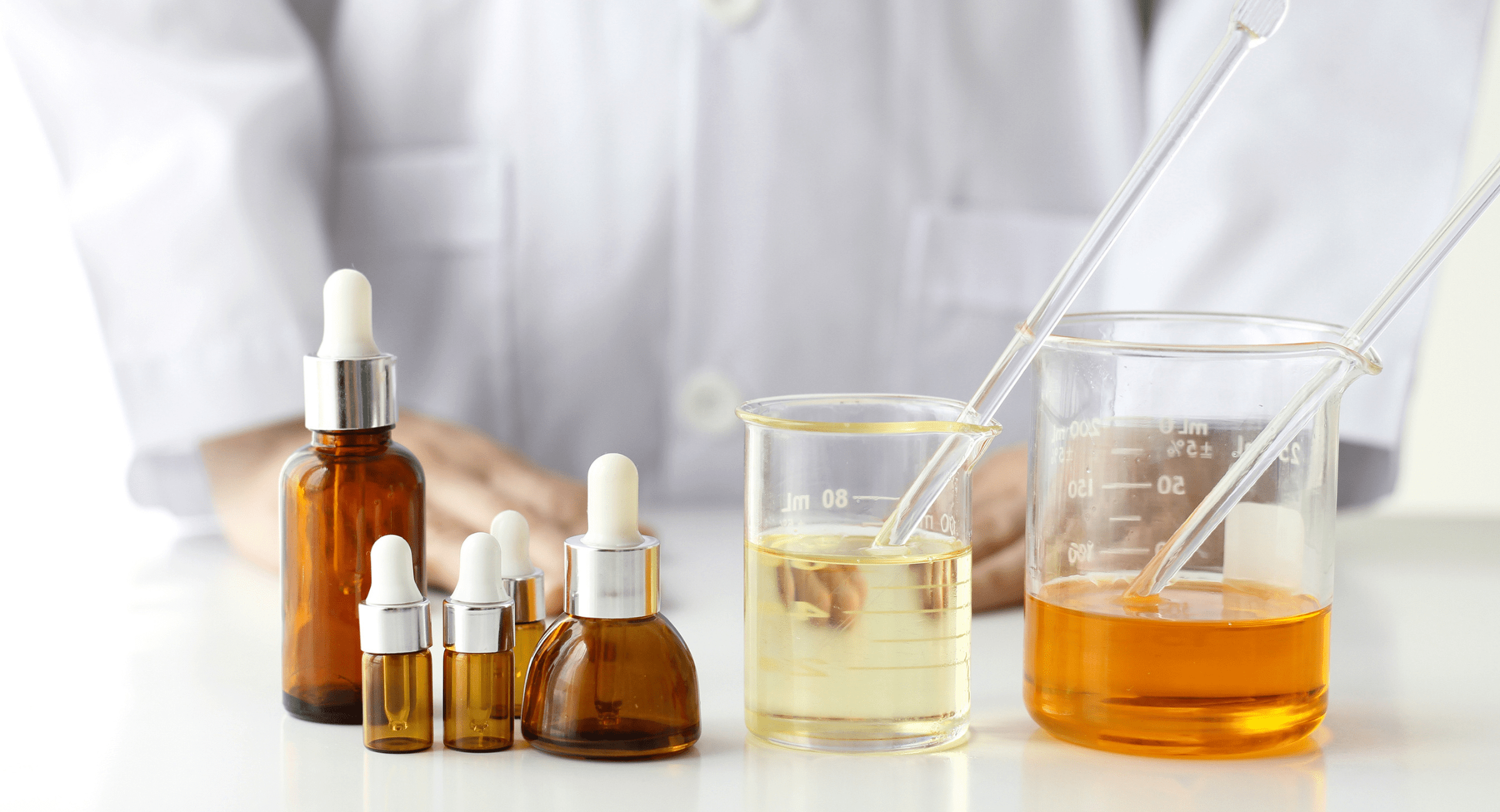 A lab-coated individual is presenting a bottle of liquid