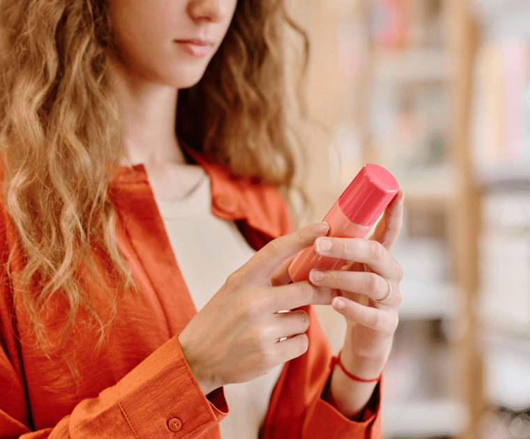 A woman displays a pink lipstick tube