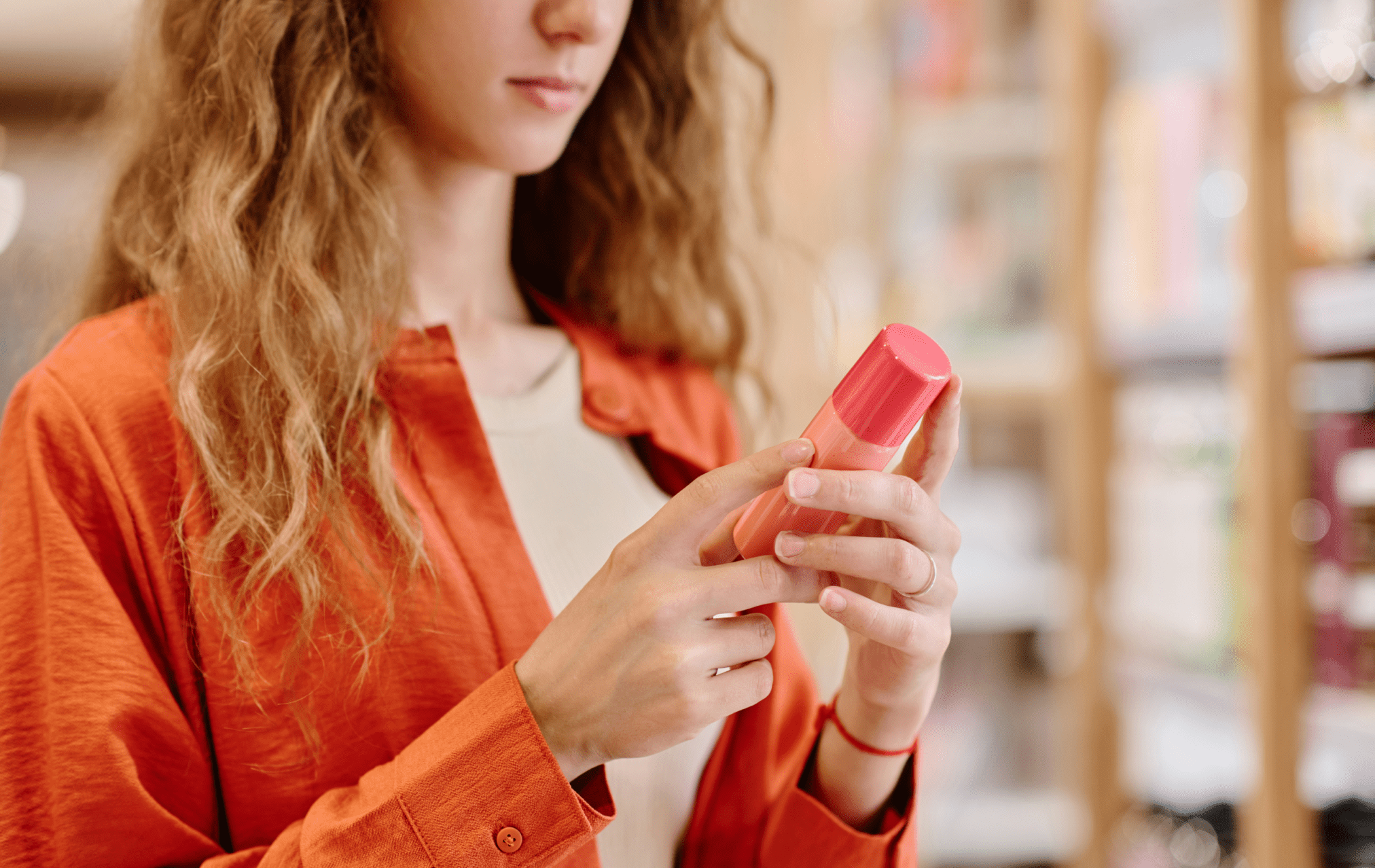 A woman displays a pink lipstick tube
